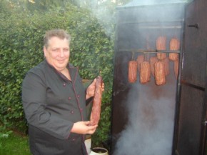 Fleischermeister mit geräucherten Schinken